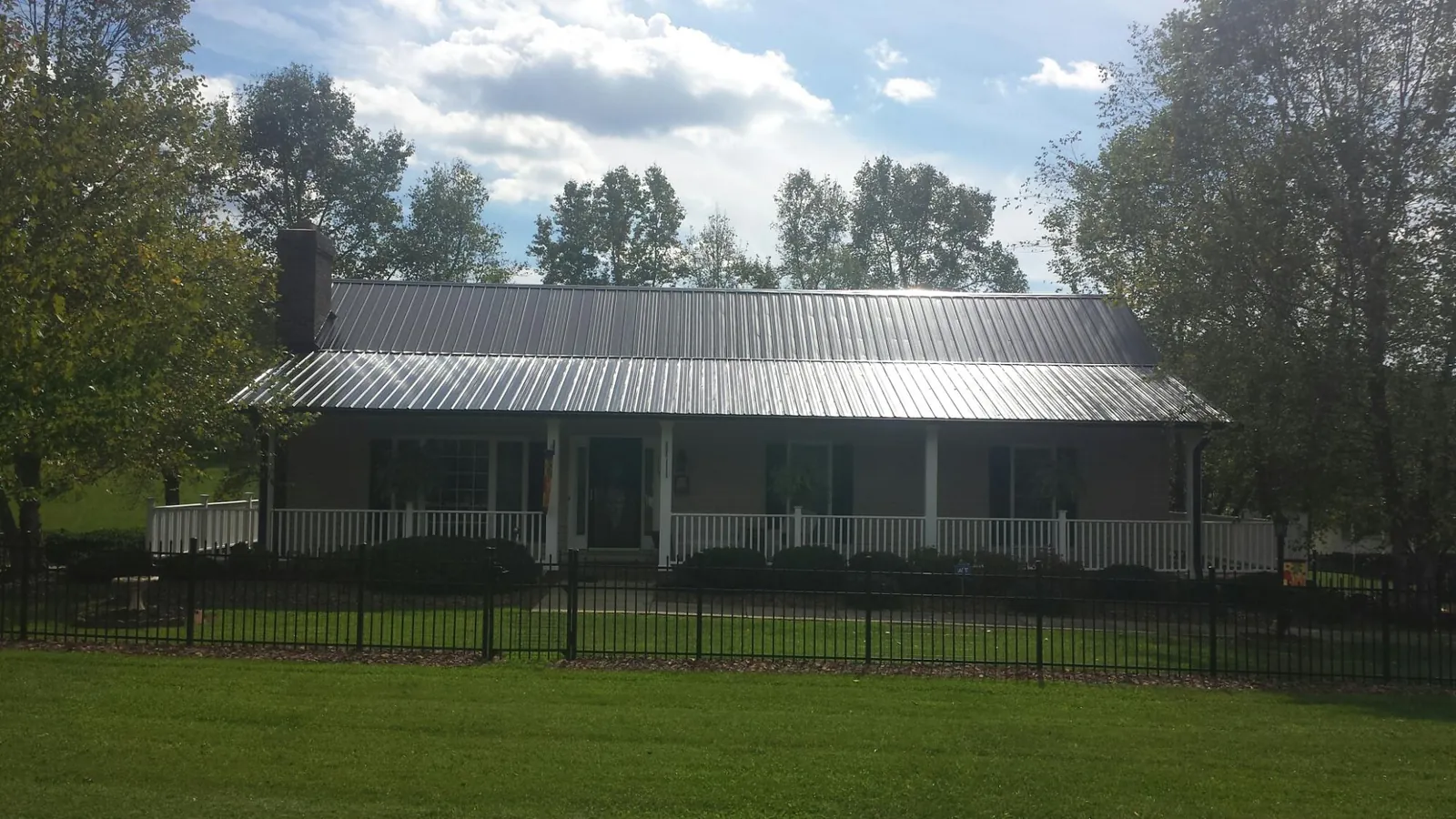 Gray metal roof on a brick ranch with a full width front porch — Gutter Guard Installation work by our crew in Winnetka